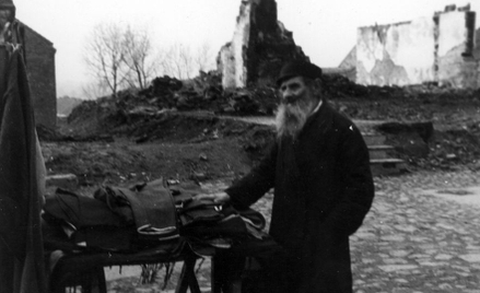 Uliczna sprzedaż ubrań przez starego Żyda wśród ruin