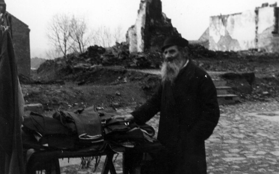 Uliczna sprzedaż ubrań przez starego Żyda wśród ruin