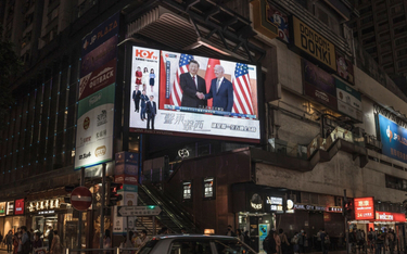 Prezydent USA Joe Biden ściska dłoń prezydenta Chin Xi Jinpinga na telebimie w Pekinie, ale w dziedz