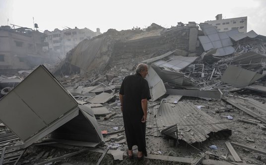 Palestyńczyk na gruzach zniszczonego w wyniku nalotu sił izraelskich wieżowca Al-Watan w Gazie