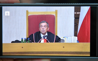 Sędzia Trybunału Konstytucyjnego Bartłomiej Sochański podczas obrad oglądanych na ekranie telefonu p