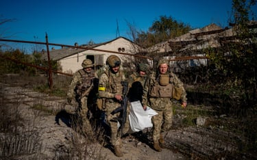 Ukraińscy żołnierze niosą ciało poległego kolegi