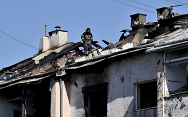 Ratownik sprawdza dach uszkodzonego budynku mieszkalnego po ataku rakietowym na Lwów, 15 sierpnia 20