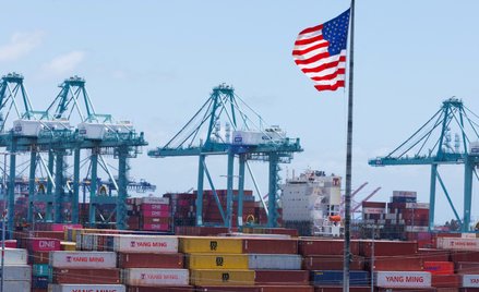 Amerykańska flaga powiewa nad statkiem i kontenerami transportowymi w porcie Los Angeles w San Pedro