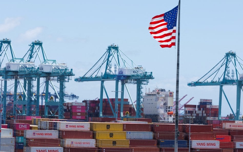 Amerykańska flaga powiewa nad statkiem i kontenerami transportowymi w porcie Los Angeles w San Pedro