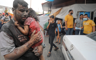 Ranny Palestyńczyk z dzieckiem przed szpitalem w mieście Gaza