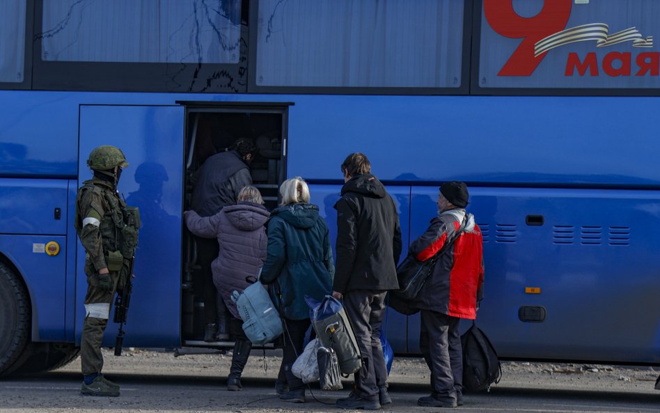 Rosyjscy żołnierze kontrolujący wsiadanie do autobusu cywilów ewakuowanych z Azowstalu w Mariupolu