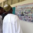 Mieszkańcy Maiduguri analizują plakat nigeryjskiej armii przedstawiający podobizny setki podejrzanyc