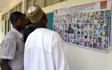 Mieszkańcy Maiduguri analizują plakat nigeryjskiej armii przedstawiający podobizny setki podejrzanyc