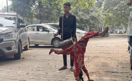 Mała akrobatka i przygrywający jej na bębnie chłopak nie dają się przegonić sprzed bramy wjazdowej d