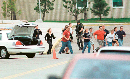 Students run from Columbine High School run under cover from police 20 April 1999 in Littleton, Colo