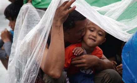 Filipińczyk, który ocalał z tajfunu, czeka z synem na ewakuację na lotnisku polowym Tacloban. Oni i 