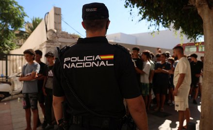Policjant na warcie przed posterunkiem policji na Ceucie. W tle nieletni migranci czekają, by zareje