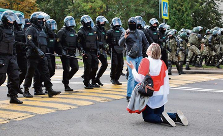 Klęcząca kobieta powstrzymuje OMON. W niedzielę w Mińsku protestowało ponad 100 tys. ludzi