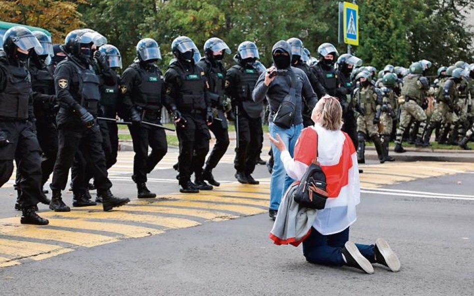 Klęcząca kobieta powstrzymuje OMON. W niedzielę w Mińsku protestowało ponad 100 tys. ludzi