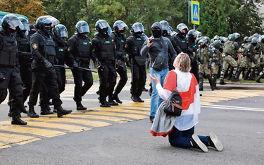 Klęcząca kobieta powstrzymuje OMON. W niedzielę w Mińsku protestowało ponad 100 tys. ludzi