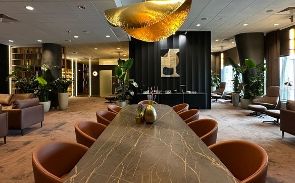 Centralna część salonu VIP, z długim, marmurowym stołem. Luksusowe oświetlenie i elegancki wystrój p