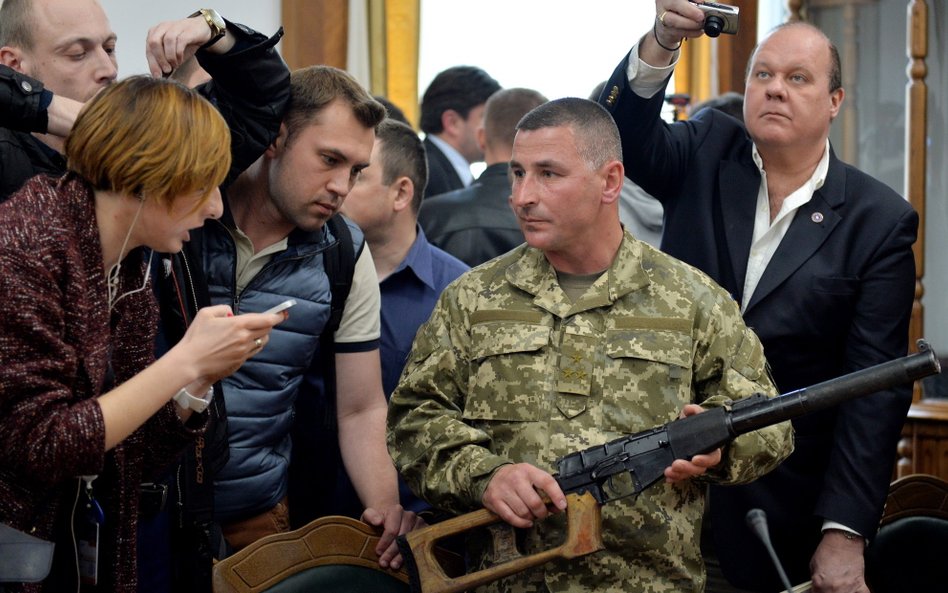 Ukraiński oficer pokazuje na konferencji prasowej broń jednego ze złapanych Rosjan: 9-milimetrowy ka