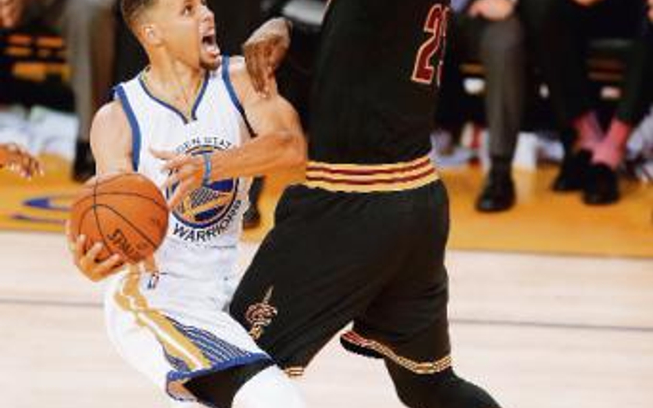 Stephen Curry z Golden State Warriors atakuje kosz, do którego dostępu broni LeBron James z Clevelan