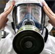 Pracownik Ministerstwa Sytuacji Nadzwyczajnych ubrany w sprzęt ochronny poprawia maskę podczas dezyn