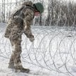Ukraiński żołnierz instaluje drut kolczasty w pobliżu linii frontu na przedmieściach Kupiańska