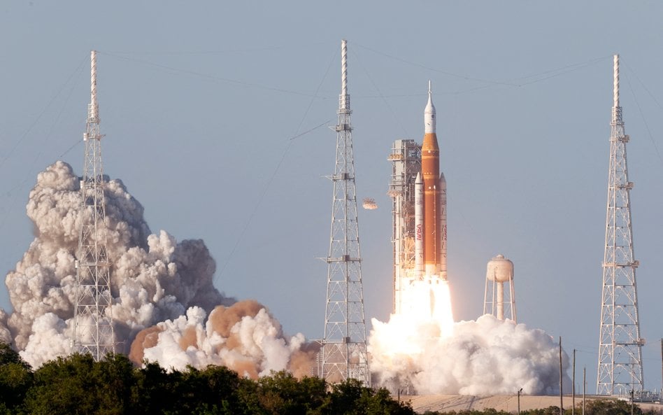 Rakieta Space Launch System o wysokości 98 metrów, wynosząca kapsułę załogową Orion z astronautami m