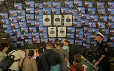 Ludzie gromadzą się w pobliżu portretów odznaczonych rosyjskich żołnierzy, w tym poległych podczas k