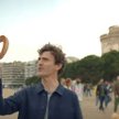 Bohater filmu reklamowego zachęca do kosztowania lokalnego jedzenia. Na zdjęciu z preclem w Salonika