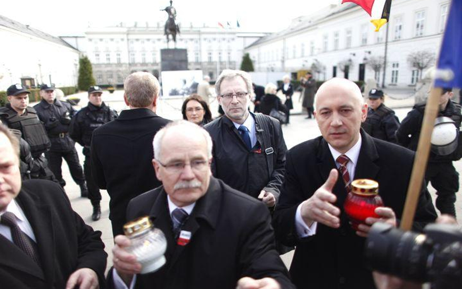 Joachim Brudziński (z prawej) wraz z innymi parlamentarzystami PiS odbiera znicze od ludzi, którzy n