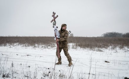 Ukraiński żołnierz niesie podczas ceremonii pogrzebowej w Słowiańsku krzyż, który stanie na grobie j