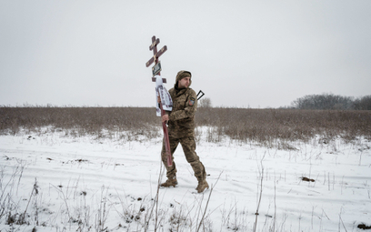 Ukraiński żołnierz niesie podczas ceremonii pogrzebowej w Słowiańsku krzyż, który stanie na grobie j
