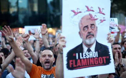 Protestujący trzyma transparent z wizerunkiem premiera Albanii Ediego Ramy podczas demonstracji prze