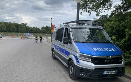 Policyjny radiowóz i funkcjonariusze dbający o bezpieczeństwo wokół PGE Narodowego