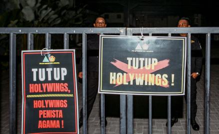 Tablice z hasłami "Zamknąć Holywings" i "Holywings bluźnierca" przed barem Holywings w Dżakarcie, fo