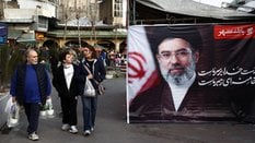 Ludzie obok transparentu ze zdjęciem nowego Najwyższego Przywódcy Iranu, Modżty Chameneiego, na baza