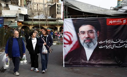 Ludzie obok transparentu ze zdjęciem nowego Najwyższego Przywódcy Iranu, Modżty Chameneiego, na baza