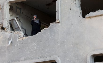 Kobieta wygląda z okna budynku, który ucierpiał w nalocie na Teheran