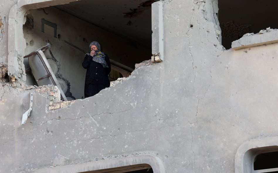 Kobieta wygląda z okna budynku, który ucierpiał w nalocie na Teheran