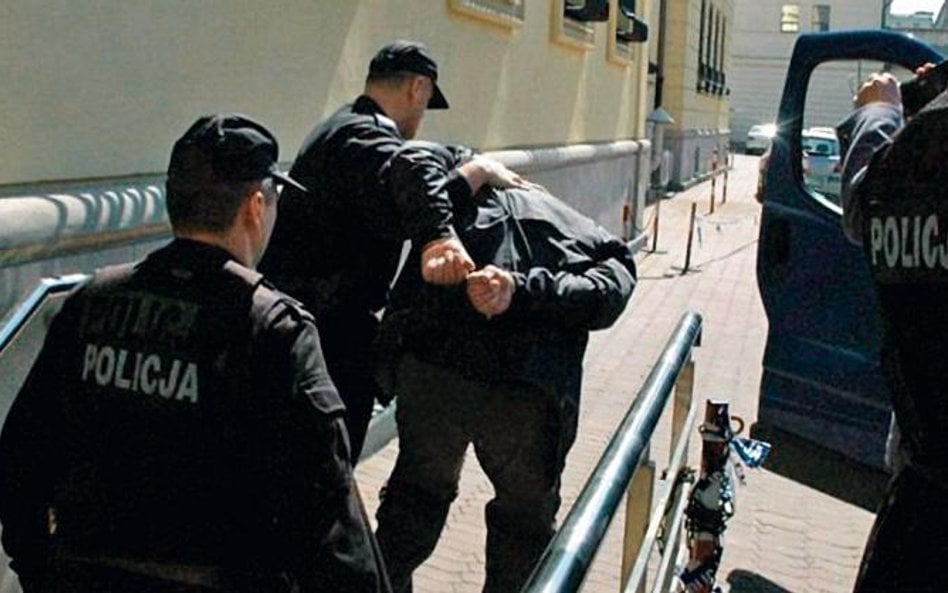 Policjanci z Centralnego Biura Śledczego prowadzą skutego kajdankami Marka Cz.