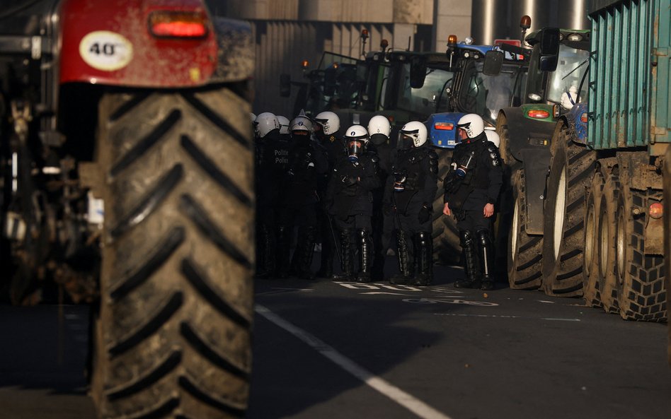 Policjanci stoją obok traktorów, podczas gdy rolnicy protestują przeciwko umowie o wolnym handlu mię