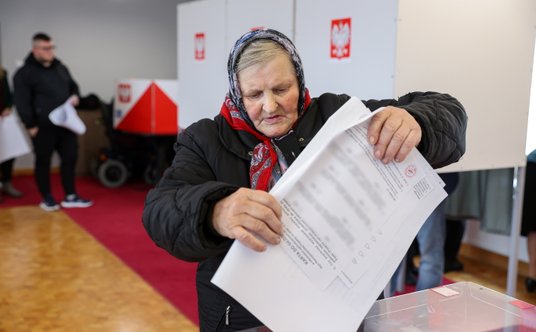 Kobieta w tradycyjnej łowickiej chuście głosuje w lokalu wyborczym w Głuchowie koło Rawy Mazowieckie