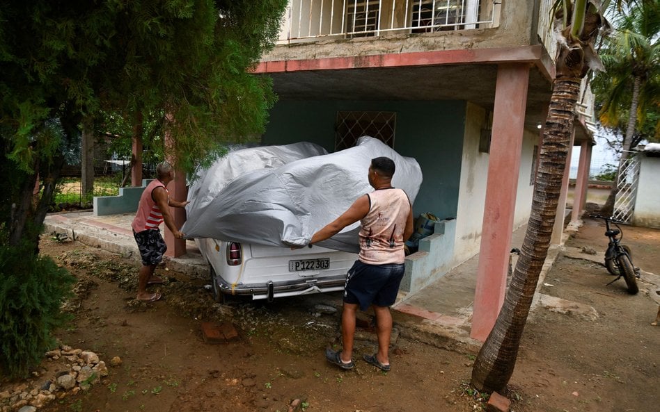 Dwaj mężczyźni zabezpieczają samochód przed nadejściem huraganu Melissa, Santiago de Cuba na Kubie