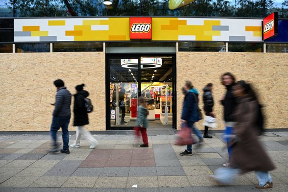 Ludzie mijają sklep Lego zabezpieczony drewnianymi deskami przed spodziewanymi protestami ruchu młod