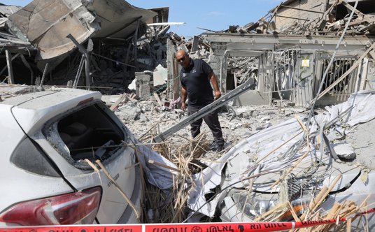 Izraelski policjant obok zniszczonego budynku w Tel Awiwie