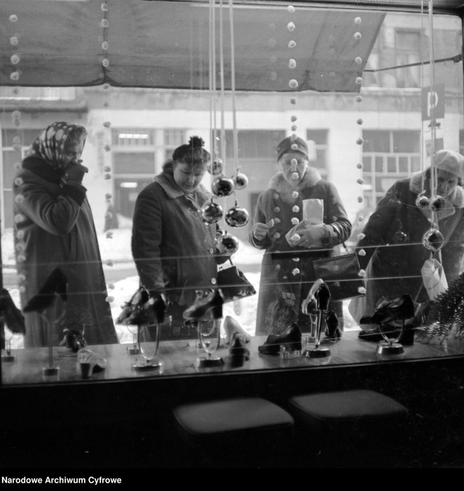 Udekorowana świątecznie witryna z obuwiem - widok od strony sklepu. Przez szybę widoczni przechodnie