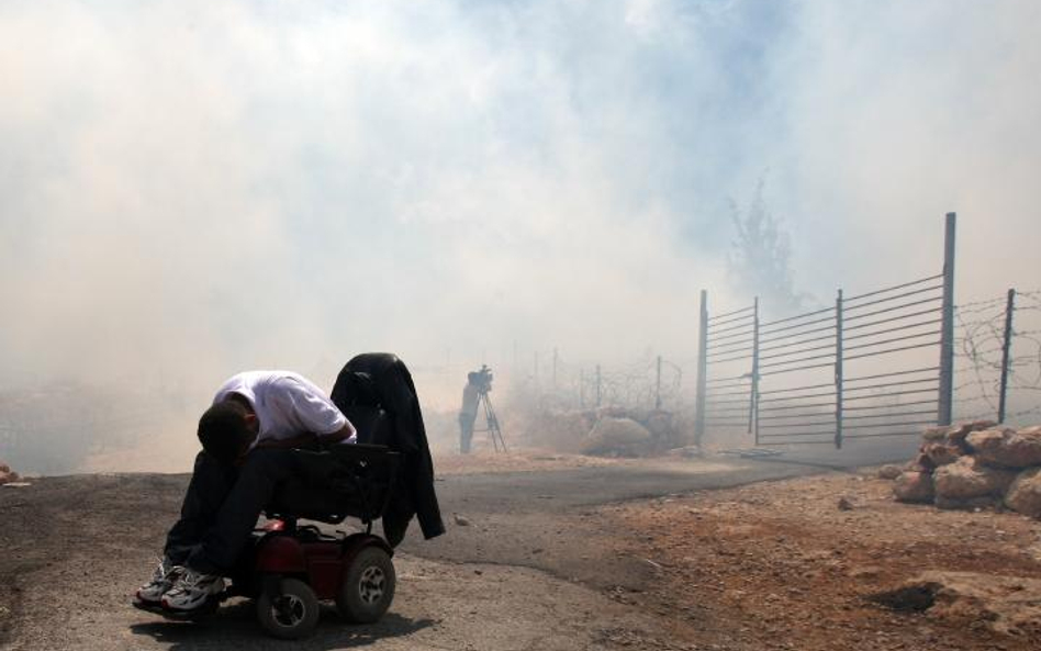 Izrael, Zachodni Brzeg Jordanu. Palestyńczyk protestujący przeciwko izraelskiemu murowi zakrywa twar