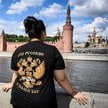 Kobieta ubrana w koszulkę z godłem państwowym Rosji i napisem „Jesteśmy Rosjanami, Bóg z nami” stoi 