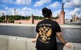 Kobieta ubrana w koszulkę z godłem państwowym Rosji i napisem „Jesteśmy Rosjanami, Bóg z nami” stoi 