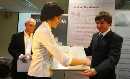 Nagrodę wręcza syn Andrzeja Bączkowskiego - Mateusz Bączkowski. Z tyłu sekretarz stanu w Kancelarii 