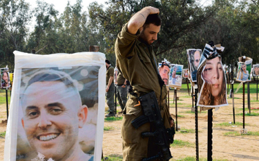 Izraelski żołnierz w miejscu, w którym odbywał się festiwal Supernova, wśród zdjęć ofiar ataku z 7 p